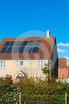 Solar photovoltaic panel array on house roof against a blue sky