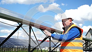 Solar plant worker tightens battery bolts during maintenance check. Engineer servicing solar panels.