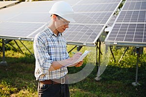 Solar power plant. Man standing near solar panels. Renewable energy