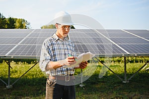 Solar power plant. Man standing near solar panels. Renewable energy