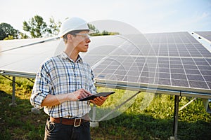 Solar power plant. Man standing near solar panels. Renewable energy