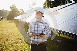 Solar power plant. Man standing near solar panels. Renewable energy