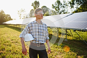 Solar power plant. Man standing near solar panels. Renewable energy