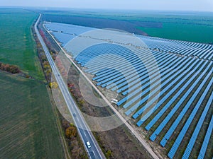 Solar power station in green field near road. Aerial view. Alternative energy, ecology power conservation concept