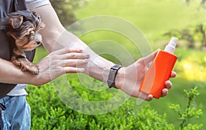 Solar protection. Hand of man applying sun cream & x28;sunscreen& x29; to protect skin during walking in the park with dog.