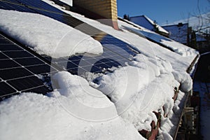 Solar PV panels covered by snow on the home roof during winter on a sunny day