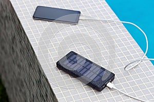 Solar smartphone charger charging phone at swimming pool