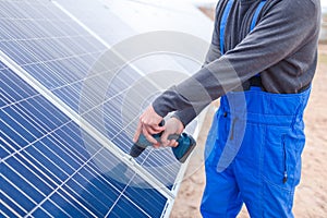 A solar station worker drills a solar battery panel.
