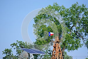 Solar Water well with Texas Windmill in front of summer green trees, farm ranch fence and blue sky background