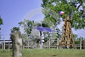 Solar Water well with Texas Windmill in front of summer green trees, farm ranch fence and blue sky background