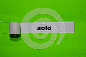 SOLD, Inspiration and business concept on green torn paper