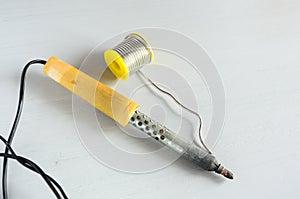 Solder wire and soldering iron with wooden handle on gray background