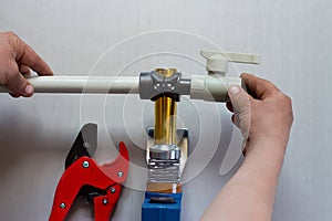 Soldering iron for polypropylene plumbing pipes. The hands of the plumber are holding the pipeline parts.