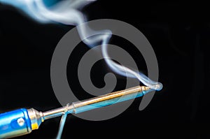 soldering iron with smoke on a black background. Electrical