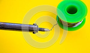 Soldering iron, tin, rosin on a yellow background. Macro. Repair of electrical equipment, radio engineering. Solder wires,