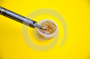 Soldering iron, tin, rosin on a yellow background. Macro. Repair of electrical equipment, radio engineering. Solder wires,