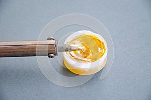 Soldering iron, tin, rosin on a yellow background. Macro. Repair of electrical equipment, radio engineering. Solder wires,