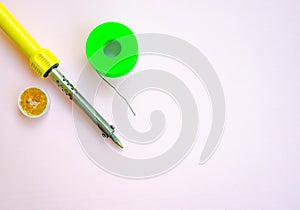 Soldering iron, tin, rosin on a yellow background. Macro. Repair of electrical equipment, radio engineering. Solder wires,