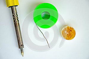 Soldering iron, tin, rosin on a yellow background. Macro. Repair of electrical equipment, radio engineering. Solder wires,