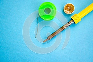 Soldering iron, tin, rosin on a yellow background. Macro. Repair of electrical equipment, radio engineering. Solder wires,