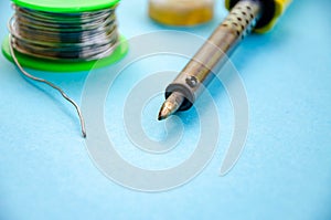 Soldering iron, tin, rosin on a yellow background. Macro. Repair of electrical equipment, radio engineering. Solder wires,