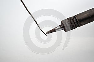 Soldering iron touching wire on a white background