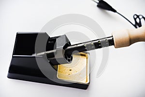 Soldering iron with a wooden handle in the holder. A soldering iron stand
