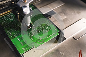 Soldering paste dispenser machine in use. Professional machine glueing electric components onto green PCB. Modern