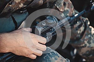 A soldier adjusts optical sight on a rifle.