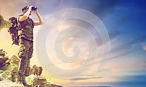 Soldier with backpack looking to binocular