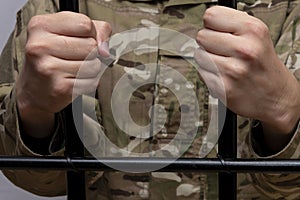 Soldier behind bars in a courtroom against a light background. Concept: trial of a soldier, desertion in the army, prisoner of war