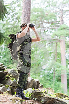 Soldier with binocular and backpack in forest