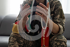 Soldier in camouflage with a rosary in her hands