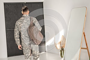 Soldier in the camouflage uniform leaving his home