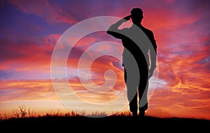 Soldier full body silhouette saluting gesture at sunset copy space