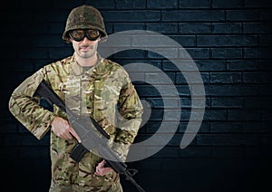 soldier with helmet, glasses and weapon. dark bricks background