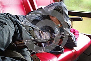 Soldier holds a machine gun between his legs while he is having a siesta an a journey coach