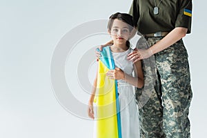 Soldier hugging child with ukrainian flag