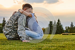 Soldier hugging with wife against evening sky background.