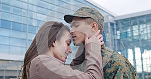 Soldier kissing wife in forcehead.