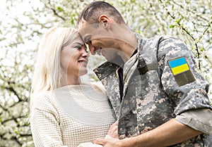 Soldier in military uniform reunited with his family and Ukrainian flag