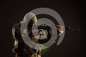 Soldier militia saboteur in military clothing with a Kalashnikov rifle on a dark background