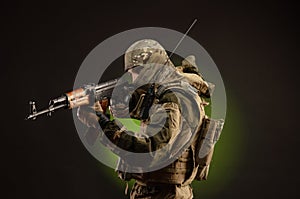 Soldier militia saboteur in military clothing with a Kalashnikov rifle on a dark background