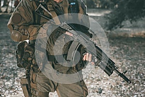 The soldier in the performance of tasks in camouflage and protective gloves holding a gun.