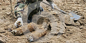 Military personnel extracting live mortar shell during demining operation