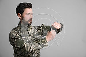 Soldier pulling safety pin out of hand grenade on light grey background. Military service