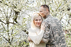 Soldier reunited with wife in park.