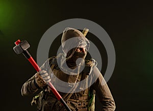 A soldier-saboteur rebel in military clothing with a weapon on a dark background holding a sledgehammer