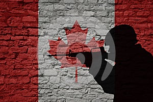 Soldier silhouette on the old brick wall with flag of canada country