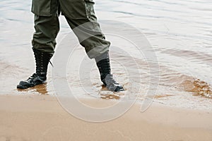 A soldier in special military clothes and boots stands in the water